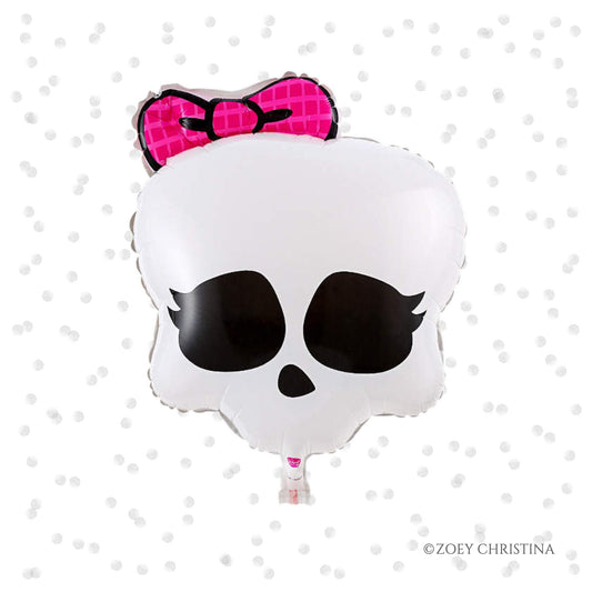 A foil balloon shaped like a skull with a pink bow on top.